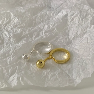 Minimalist gold and silver chain ball rings on white textured paper background