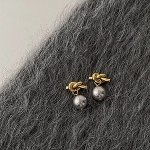 Detail of vintage gold knot earrings with grey pearls on soft plush fabric