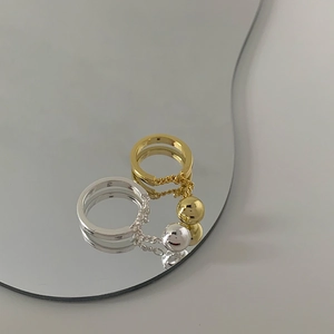 Set of gold and silver minimalist chain ball rings on a mirror surface background