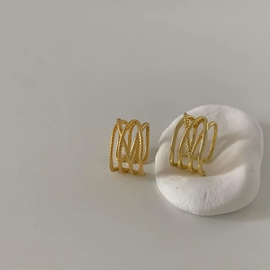 Macro shot of gold layered crossover ear cuff with twisted rope texture details