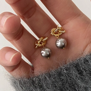 Detail of vintage French knot stud earrings with grey pearls held in hand for scale