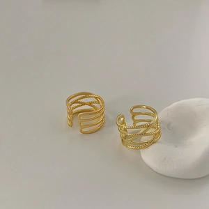 Detail of gold multilayer crisscross rings featuring smooth and braided texture bands