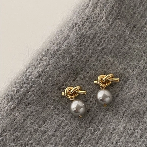 Macro shot of French vintage gold knot earrings with grey-purple pearl drops on grey fabric