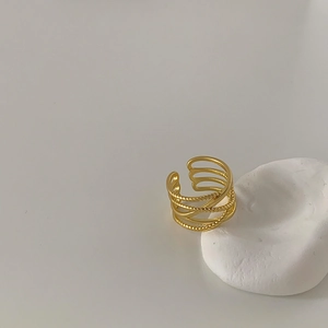 Macro shot of multi-layer crisscross gold adjustable ring on white stone base