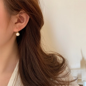 Gros plan de boucles d'oreilles pendantes en perles de coton avec crochets dorés chics