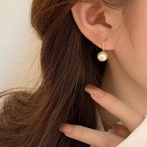 Gros plan de boucles d'oreilles élégantes en perles de coton dorées sur le modèle