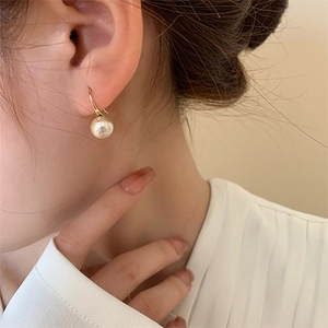 Gros plan détaillé d'une boucle d'oreille en perle de coton mate avec crochet plaqué or