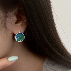 Close-up of elegant blue and green enamel drop earrings with silver finish on model