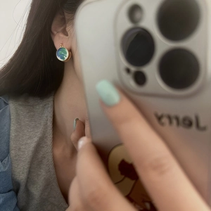 Close-up of enamel drop glaze earrings with blue and green marble texture on ears