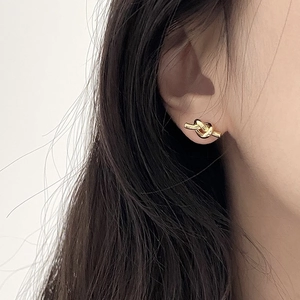 Macro detail of elegant gold knot earrings worn for a minimalist and vintage fashion style