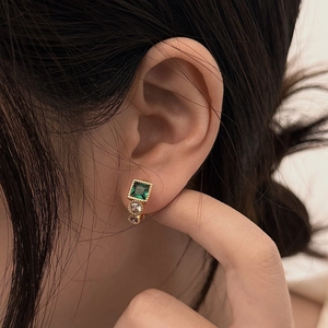 Vintage gold earrings with emerald green and purple gemstones on an Asian model