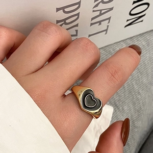 Detail of vintage gold-plated heart ring with black drip oil finish on a hand