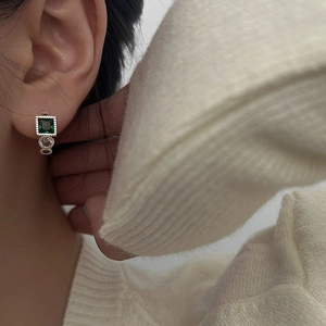 Close-up of vintage square emerald zircon earrings with silver crystal accents on a model