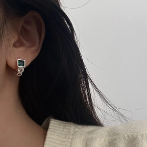 Close-up of vintage emerald green stud earrings with cubic zirconia on model