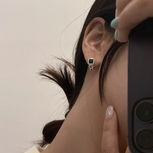 Close-up of elegant emerald green zircon earrings worn by a model in soft lighting