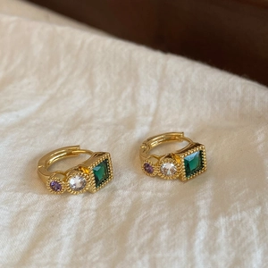 Macro detail of vintage gold earrings with emerald green and purple zircon gemstones
