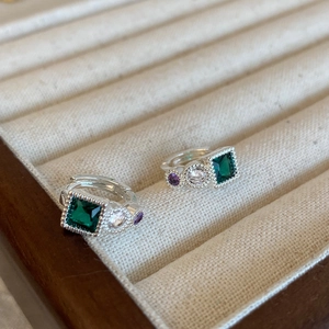 Detail of vintage emerald square stud earrings with zircons on beige velvet tray