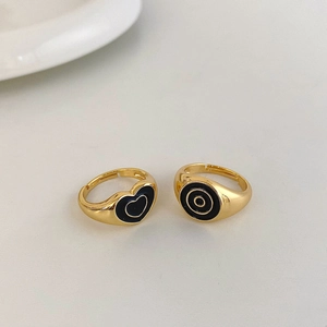 Close-up of golden rings featuring black heart and concentric circle enamel designs