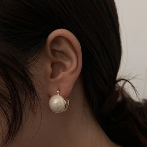 Close-up of elegant glass sphere pearl earring with a silver serrated edge on a model