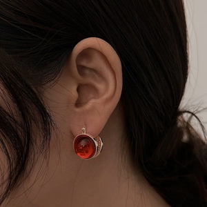 Detail shot of vintage earrings with red translucent bead and silver beaded bezel