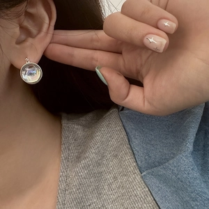 Detailed close-up of iridescent glass orb earrings with silver trim worn by a model