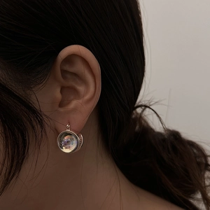 Macro shot of glass ball earrings with holographic finish and metallic textured frame