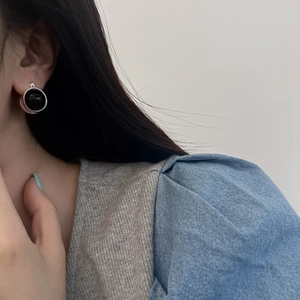 Detailed view of vintage silver twisted edge earrings with black round stone on earlobe