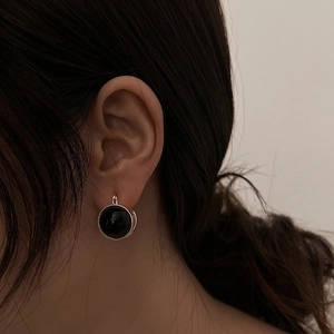 Close-up of retro black round drop earrings with silver rope borders on female model