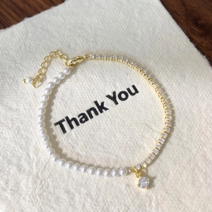 Detail of elegant pearl and zircon bracelet with gold-plated chain and lobster clasp closure