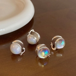Detail of round double-sided glass earrings with silver beaded edges on a wooden surface