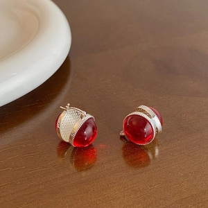 Close-up of vintage red glass ball earrings on a wooden surface with soft natural lighting