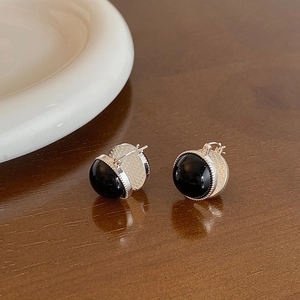 Macro shot of polished black glass bead earrings with silver beaded edges on wood