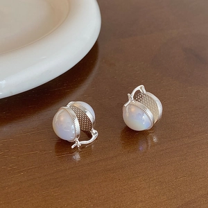 Detailed close-up of vintage hollow silver earrings with translucent white glass beads