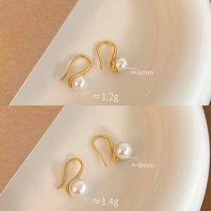 Detail view of 6mm and 8mm round pearl earrings with gold-plated hooks in two sizes