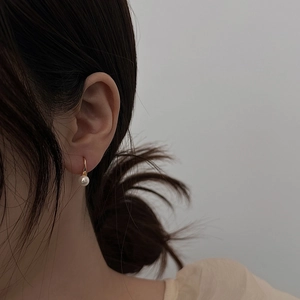 Elegant gold plated hook earrings with round white pearl drop on female model