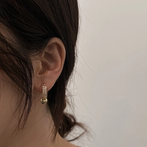 Elegant gold-plated C-shaped heart earrings with a textured finish worn by a model
