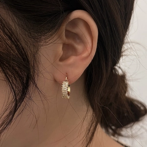 Close-up of gold heart hoop earrings with sparkling cubic zirconia on a model ear
