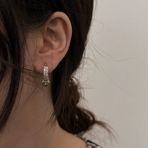 Minimalist silver heart earrings featuring zircon pavé hoops worn by a model