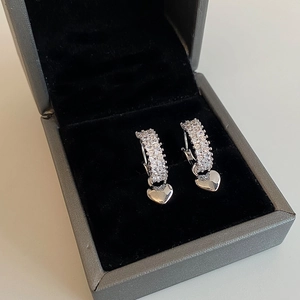 Detailed view of silver heart earrings with micro-pave zircons in a black jewelry box