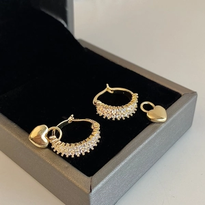 Detail of gold hoop earrings with double row of zircons and detachable heart charms