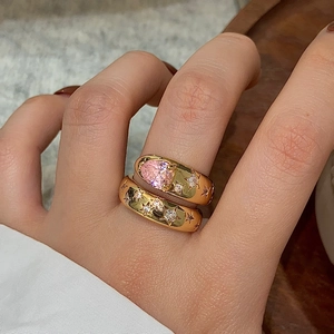 Macro shot of gold-plated rings with pink heart zircon and star carvings details