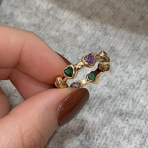 Detail of gold heart ring featuring alternating purple and green zircon stones