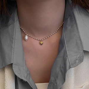 Détail du collier à mailles dorées avec pendentif cœur et perle baroque sur mannequin