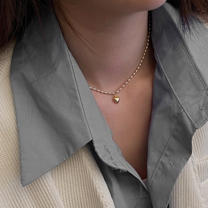 Détail d'un collier ras du cou avec pendentif cœur doré et petites perles élégantes