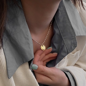 Détail d'un pendentif cœur doré à texture martelée sur une chaîne à billes en argent