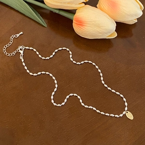 Détail du collier à billes argenté avec fermoir mousqueton et pendentif logo doré