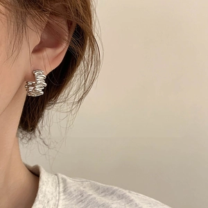 Gros plan sur une boucle d oreille créole argentée torsadée au design vintage français
