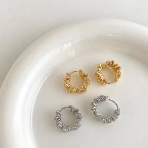 Gros plan de boucles d'oreilles créoles ondulées dorées et argentées sur plat