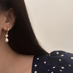 Detailed close-up of vintage baroque pearl earrings on a model with gold hoop accents