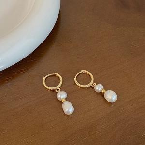 Elegant gold hoop earrings with double baroque freshwater pearls on wooden background